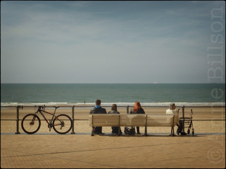 Mensen zitten of lopen naast de zee
